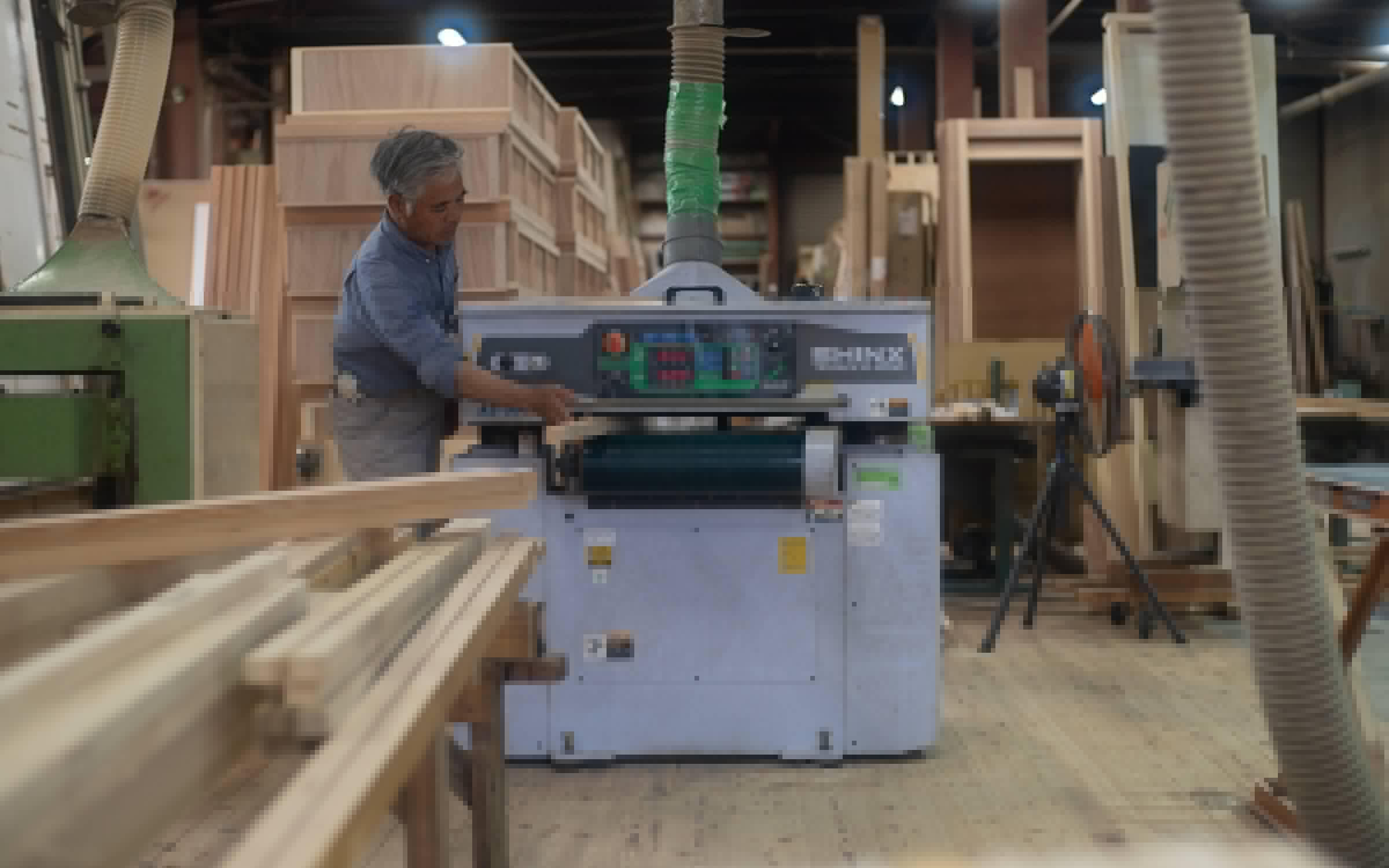 木工機械を操作しながら木材を加工する職人