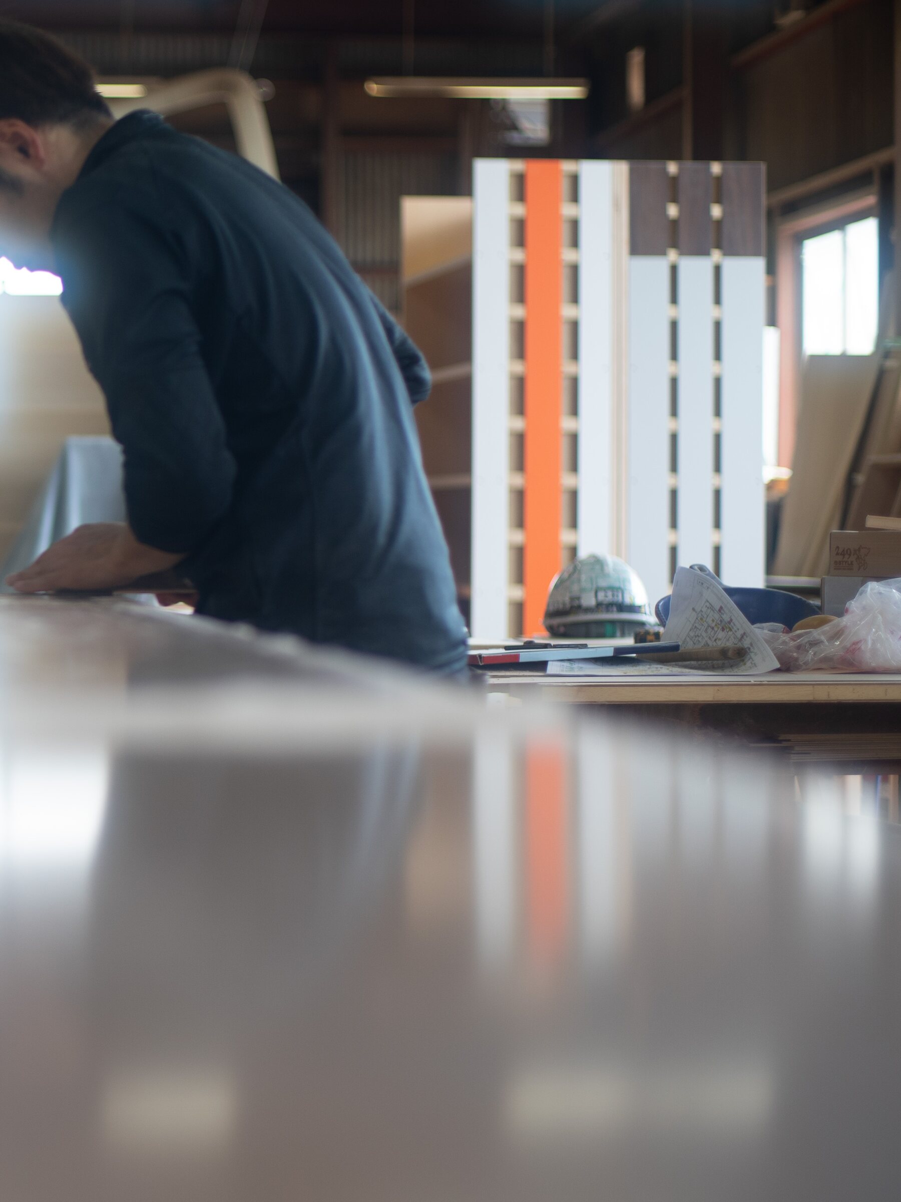工場で大型家具の表面を仕上げる若手職人